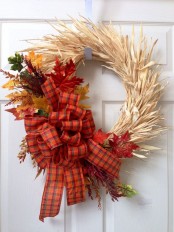 a beautiful and eye-catchy fall wreath of corn husks, bold faux leaves and a bright plaid box is a fantastic idea for outdoor fall decor