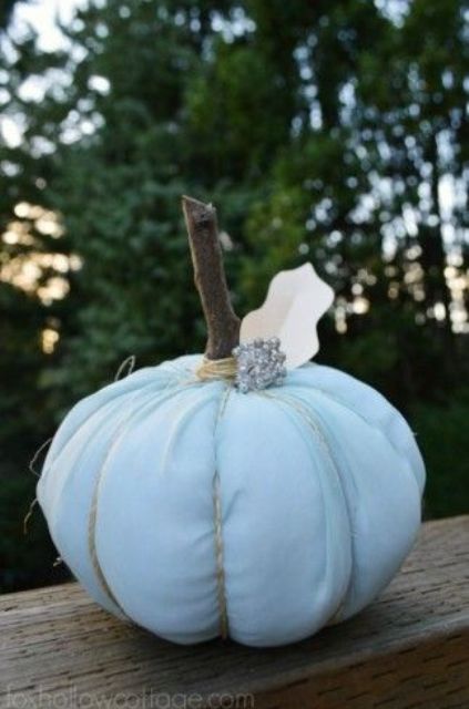 a white fabric pumpkin with a wooden stem and a brooch is a stylish idea with a glam touch