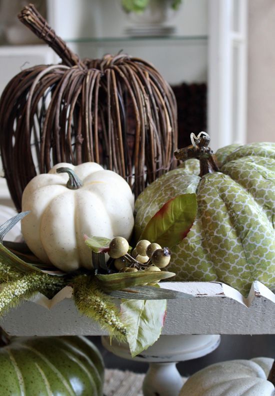 an arrangement of a vine, faux and green fabric pumpkin, greenery and berries is a stylish rustic fall centerpiece