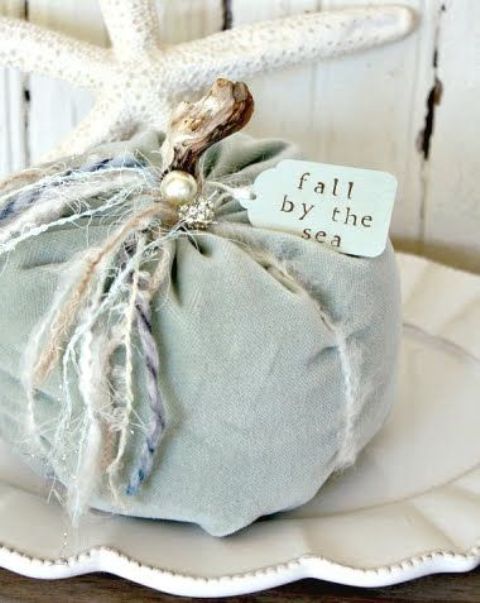 a light blue fabric pumpkin with various twine and yarn, with beads and pearls for coastal fall decor