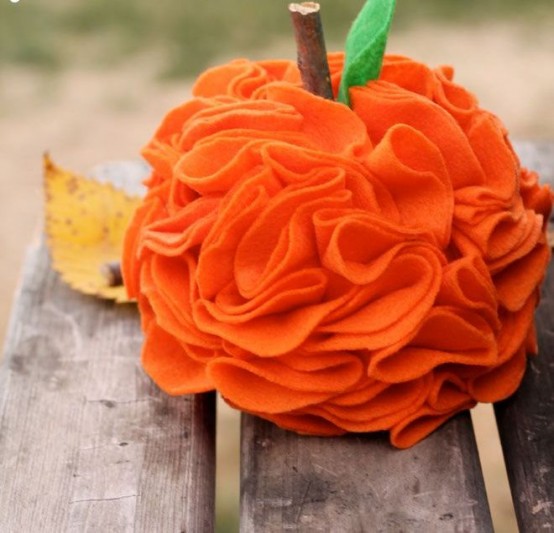 a bright orange fabric ruffle pumpkin with a wooden stem and a leaf is a fun idea for fall decor and you can DIY it