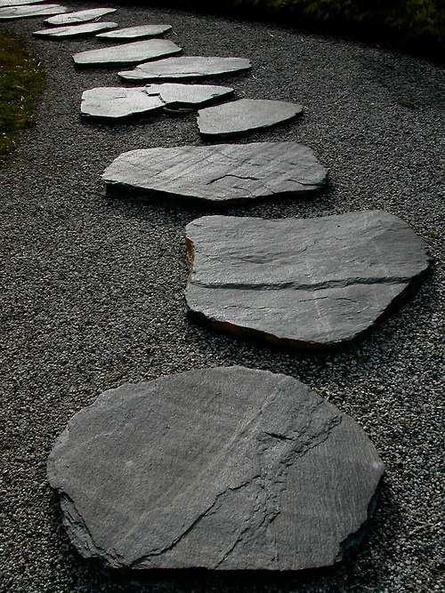 grey gravel and large rough stones for a path make up a cool and bold pathway with a zen feel