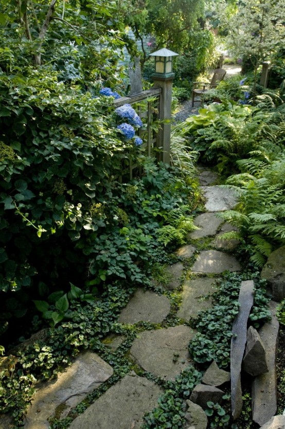 a relaxed stone garden path with greenery in between and lush foliage growing around for a calming look
