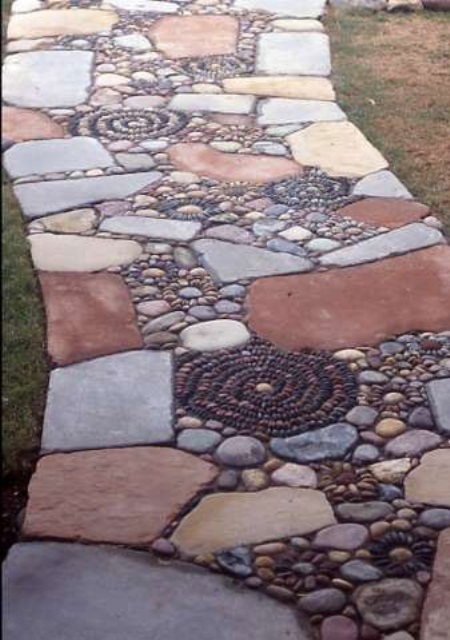 a bold and unique garden path of muted color stones and pebbles that form floral patterns