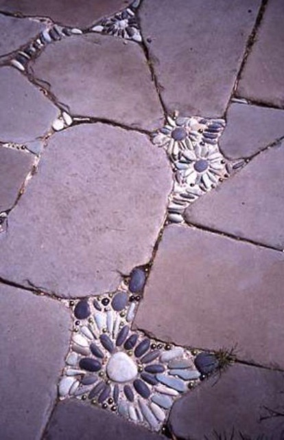 a rough stone pathway with small pebble flower inserts in it that make it bolder and cuter