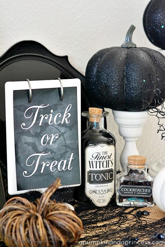 vintage Halloween decor with a stand with a black glitter pumpkin, some black liquor, a chalkboard sign and a black lace covering the table