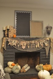a rustic Halloween mantel with cheesecloth, banners, a vintage clock, lots of pumpkins, firewood and candles in wooden candleholders