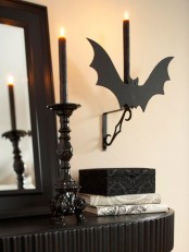 black candles in black candleholders, a black bat for decor are amazing for Halloween styling