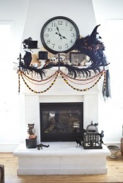a Halloween mantel with black witches’ hats, blackbirds, banners and garlands, feathers and a vintage clock
