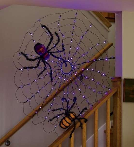 a bold decoration of a purple lit up spiderweb, large spiders in purple, orange and black is a fun and cool idea for Halloween