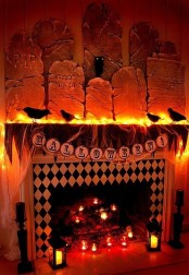 a spectacular Halloween mantel with lights, tulle, banners, blackbirds and gravestones is a great idea for Halloween, add candles and candle lanterns to the fireplace itself