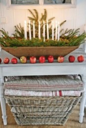 a Christmas centerpiece of a dough bowl, fir branches and thin candles plus apples along it