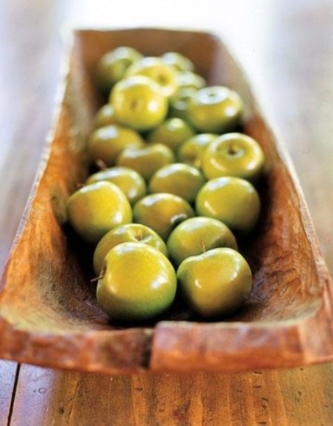 an antique dough bowl with green apples is a decoration and storage in one - ideal for kitchens