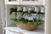 a dough bowl with fir branches and pinecones is a nice winter decoration