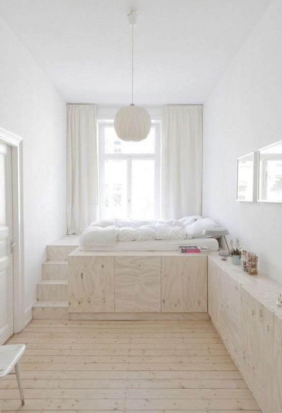 a modern airy bedroom with a raised platform with steps that hides lots of storage units inside