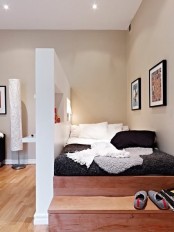 a platform bed with steps is a comfy space-saving solution separated with a wall with niche from the rest of the space