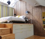 a raised wooden platform with drawers for storage to divide sleeping space and the rest of the apartment