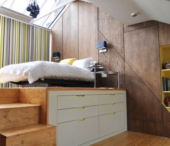 a raised wooden platform with drawers for storage to divide sleeping space and the rest of the apartment