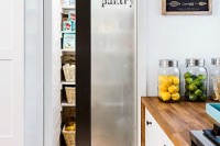 a frosted glass sliding door with dark framing and a word that marks the space behind it – a pantry