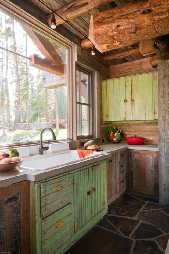 a rustic shabby chic kitchen with reclaimed and shabby cabinets, a rough wooden ceiling and beams, a view of the woodlands instead of a backsplash
