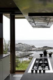 a contemporary kitchen with a jaw-dropping view, with sleek white cabinets and concrete countertops plus a kitchen island for cooking