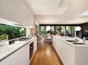 a minimalist white kitchen with sleek cabinets, built-in lights and a window backsplash that lets enjoy greenery in the garden is amazing