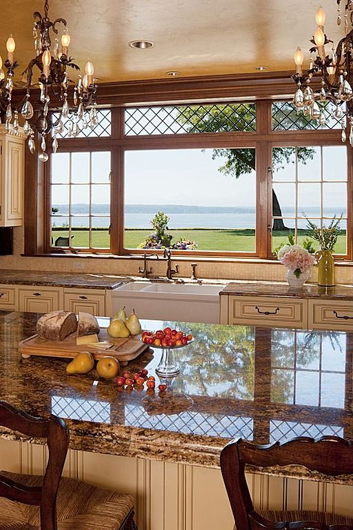 a refined vintage kitchen done in neutrals and beautiful stone, with chic vintage cabinets and crystal chandeliers plus a gorgeous sea view available
