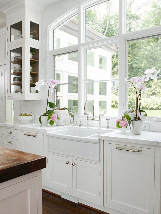 a clear white vintage kitchen with shaker style cabinets, stone countertops and a large window that lets you enjoy the views of the garden