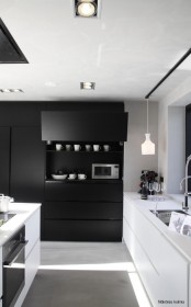 an ultra-minimalist black and white kitchen with all-sleek surfaces is a bold and contrasting idea for a modern person