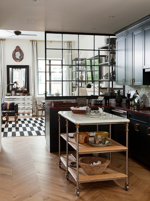 a moody kitchen with dark kitchen cabinets and light-colored wooden countertops and a marble kitchen island