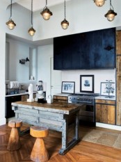 light-colored stained kitchen with black upper cabinets, pendant lamps, an industrial wood and metal kitchen island