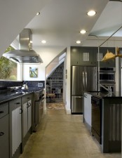 a dark green kitchen with sleek cabinets, white corrugated steel touches and built-in lights
