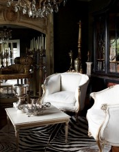 a sophisticated living room with elegant white furniture, an animal skin rug, crystal chandeliers and mirrors