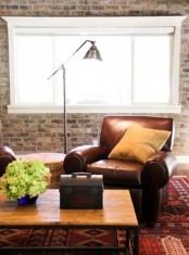 a cozy living room with leather furniture, a wooden coffee table, brick walls, a metal lamp