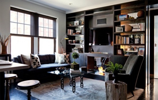 a living room with dark furniture, frames and rugs, glass tables and tree stumps as side tables