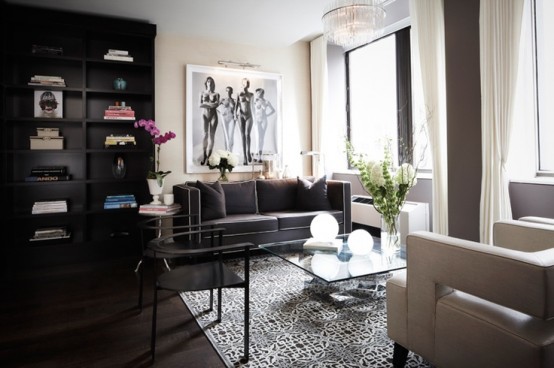 a laconic and refined living room done in neutrals and dark shades, a crystal chandelier, an artwork and neutral curtains