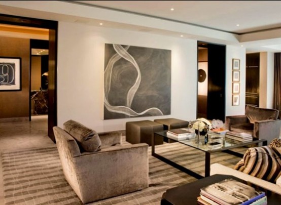 a stylish neutral living room with brown furniture, a glass coffee table and an artwork plus a neutral backdrop