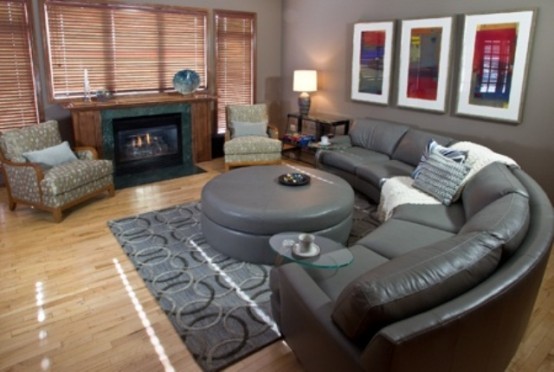 a dark living room with leather furniture, artworks, a fireplace and some glass side tables