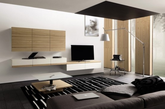 a minimalist living room with a dark sofa, a plywood storage unit, a coffee table and a wall lamp