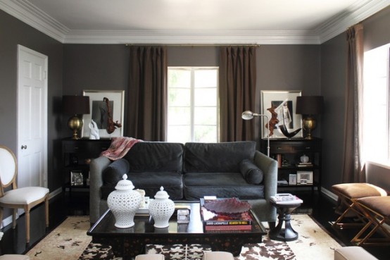 a dark living room with upholstered and leather furniture, dark curtains, some artworks and furniture