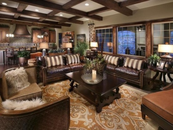 a dark living room with leather furniture, a wooden coffee table, a printed rug and faux fur pillows