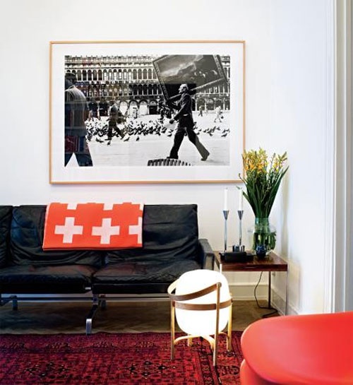 a bright living room done in white, black and red, with prints and an artwork for a bold look