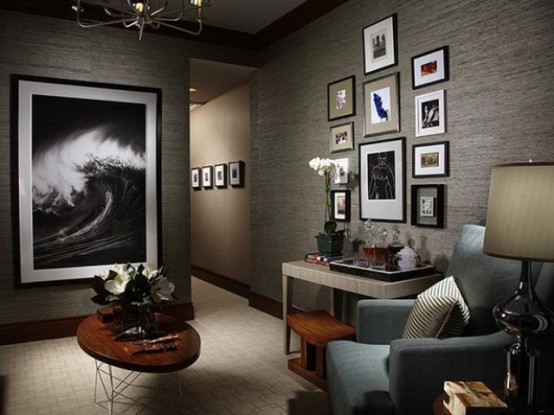 a moody masculine living room with a gallery wall, comfy aqua furniture, coffe tables and a large artrwork