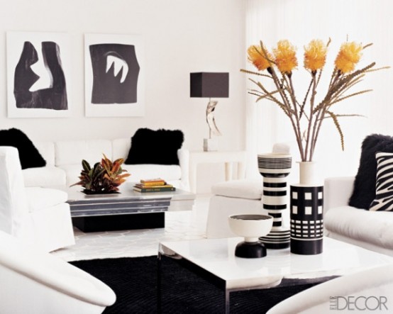 a minimalist black and white living room with rugs and fur pillows, abstract artworks and bright blooms