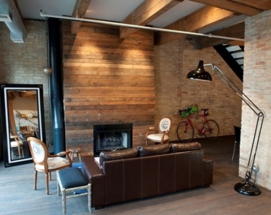 a laconic industrial living space with a wood clad fireplace wall, a floor lamp, refined chairs and a leather sofa