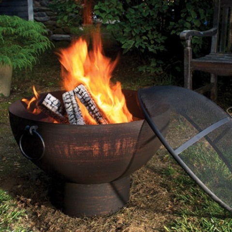 a blackened metal fire bowl with a spheric metal screen lid is a great idea for a modern outdoor space and it looks very eye-catchy while being safe