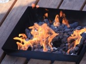 a tray-like metal fire bowl with rocks inside is a timeless idea for any outdoor space, it will match any style easily