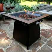 a beautiful and laconic blackened and aged metal fire bowl shaped as a square, on a tall stand is a perfect solution for a mid-century modern space