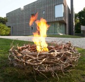 an alcohol-working fire bowl surrounded with gilded branches as a nest is a bold installation for a modern outdoor space