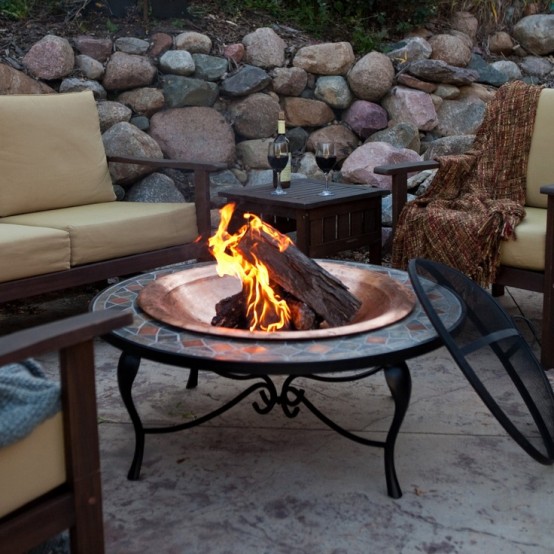 a beautiful metal and mosaic fire bowl with a copper bowl, a mosaic countertop and black legs is a gorgeous idea for a chic backyard